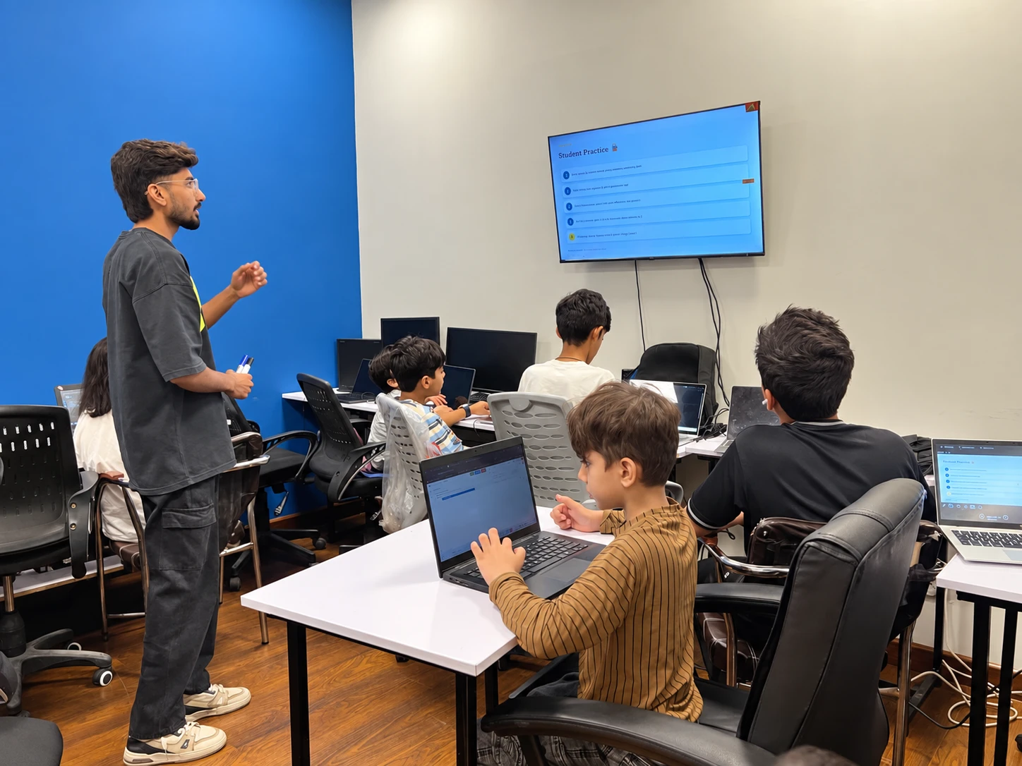 An instructor guiding children at laptops during the Python Bootcamp